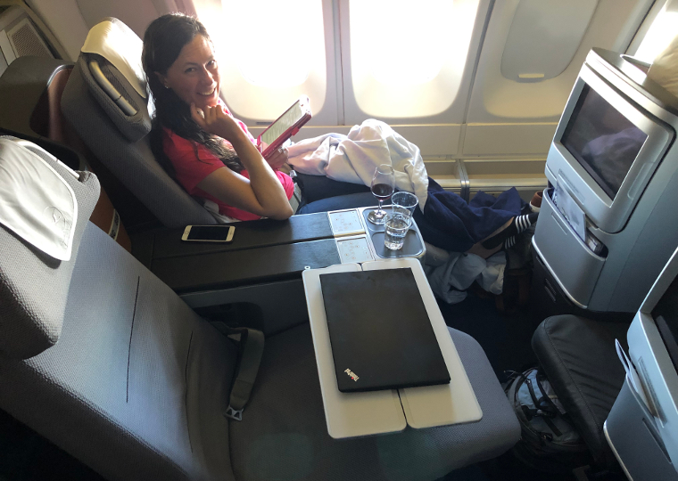 Sarah reading with her lie-flat business class seat reclined